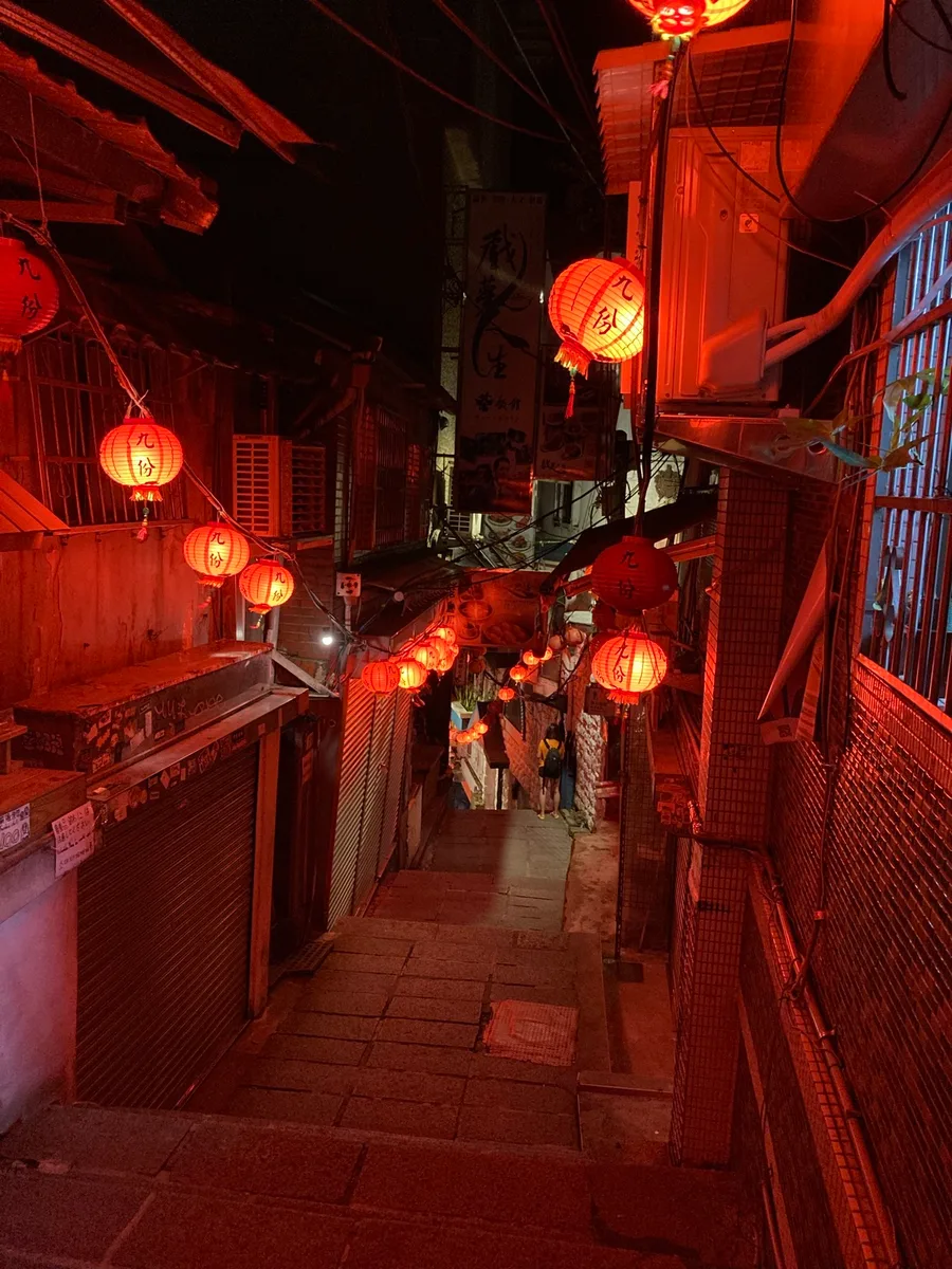 Traveler photograph of red lanterns above a narrow stone staircase in Jiufen at night